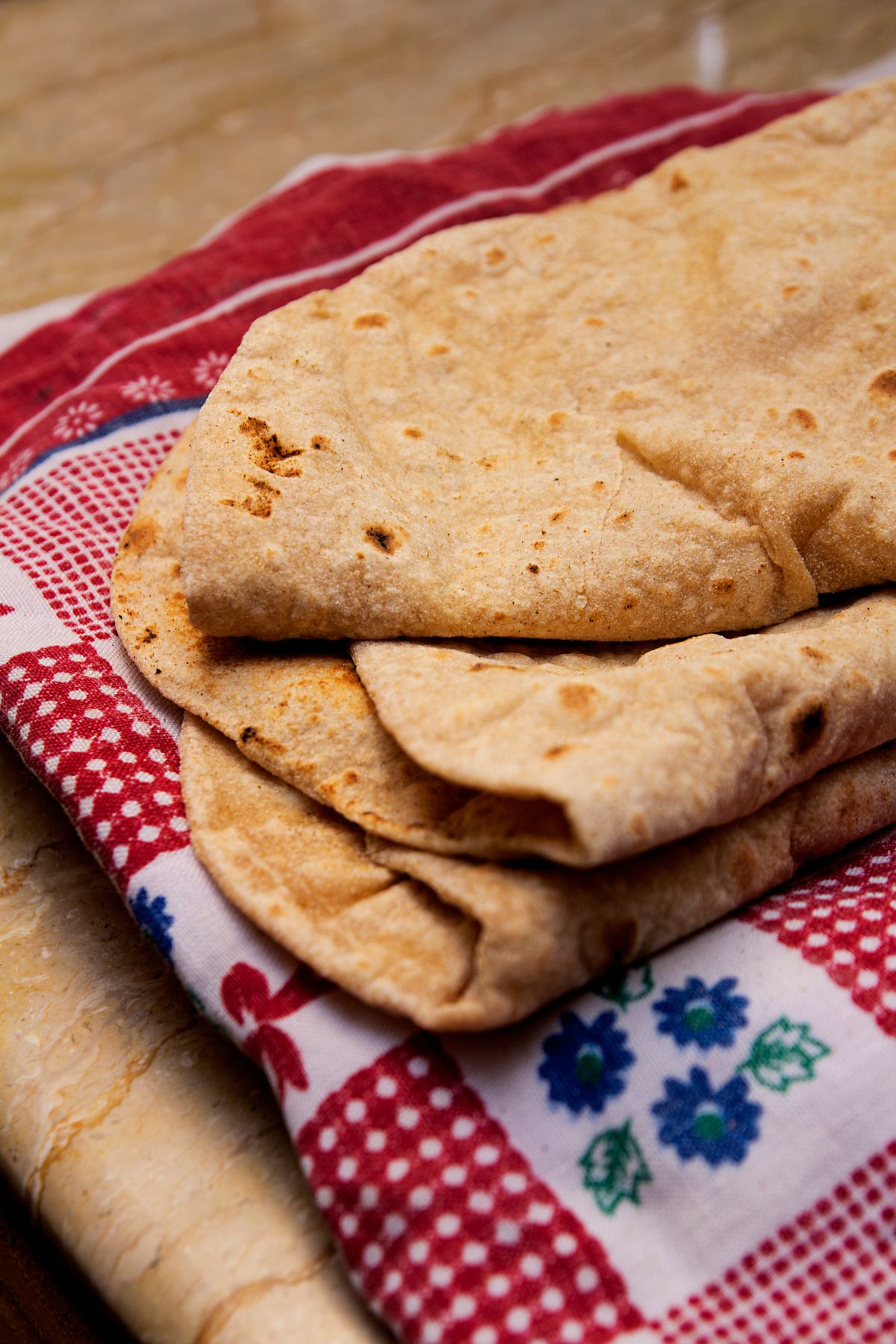 A stack of freshly made rotis on a colorful cloth